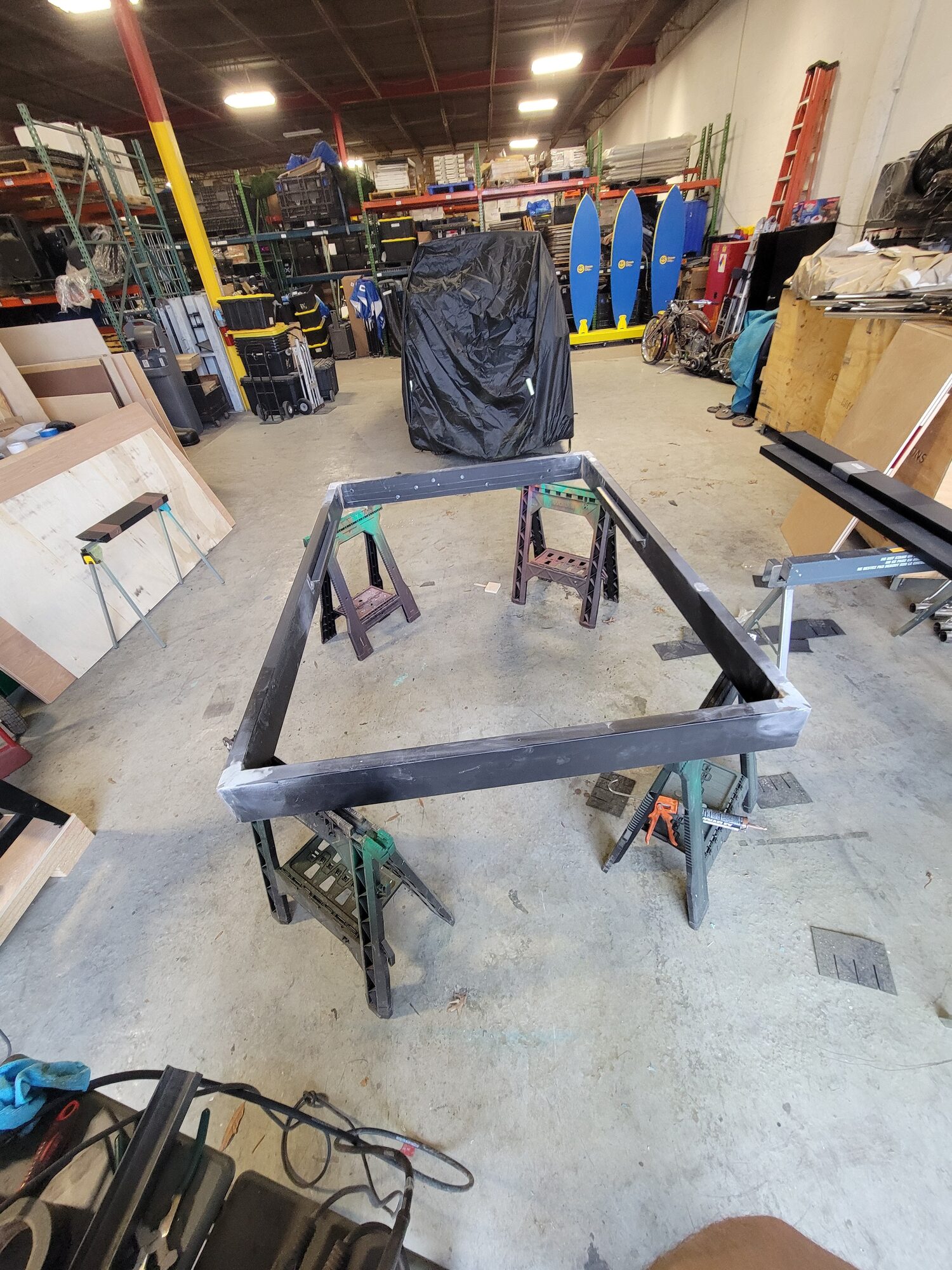 Bare unpainted steel wing frame, welded and resting on sawhorses in the shop