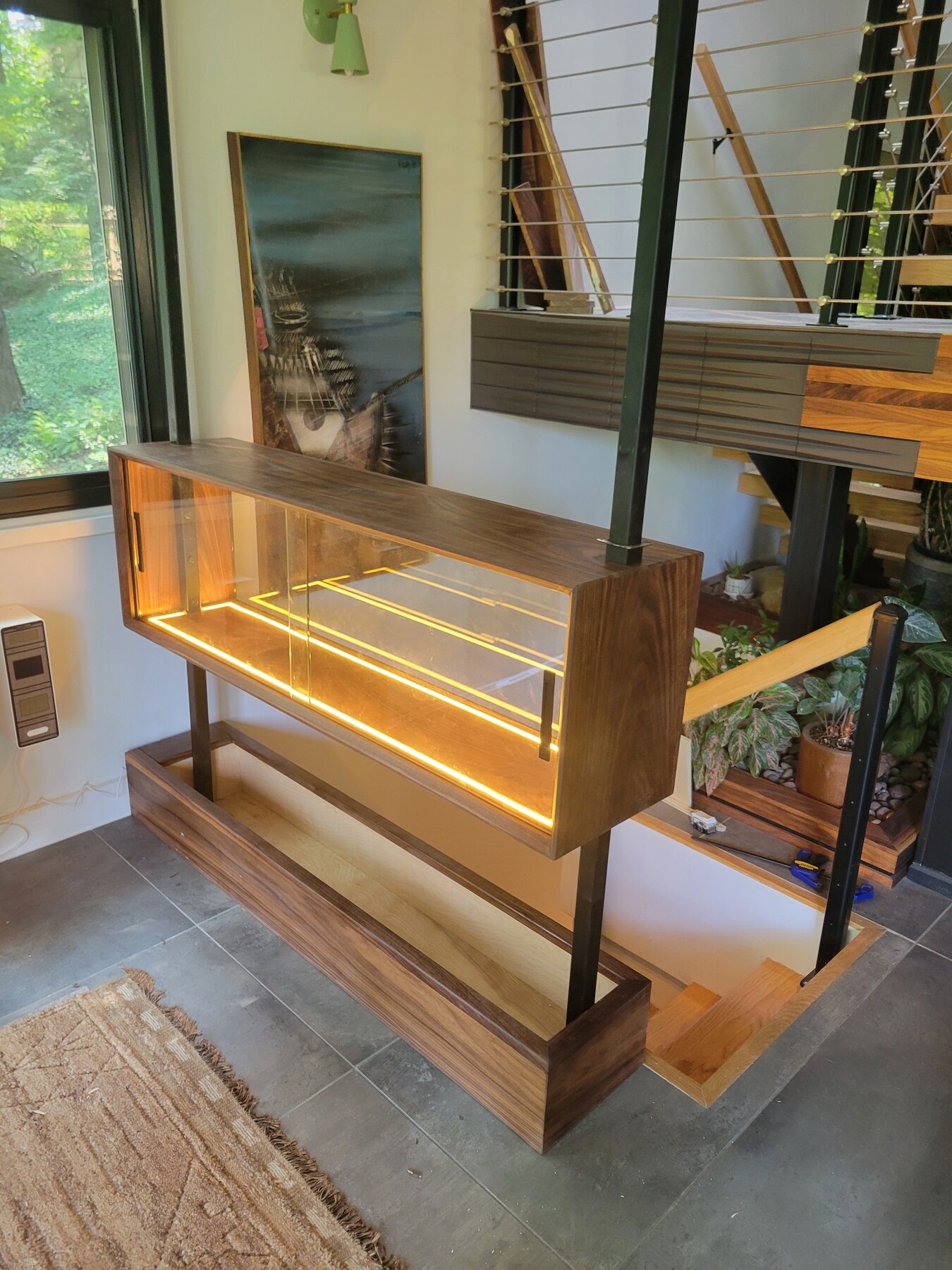 Finish carpentry, backlit walnut display cabinet with a brass-strapped mitered corner and glass front